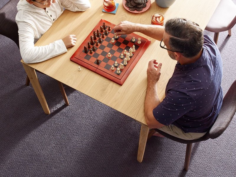 Father and son playing chess in a room with gray carpet floor from Direct Sales Floors in Danville, CA